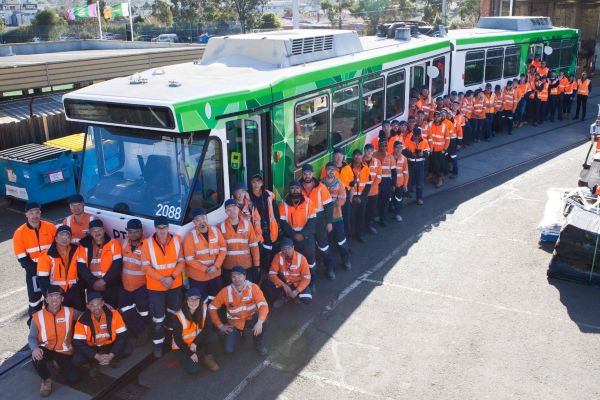 Downer employees pose with a refurbished tram
